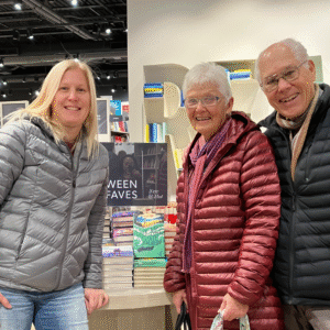 Author Sandra McTavish poses proudly with her parents next to a book display that showcases The Cricket War.